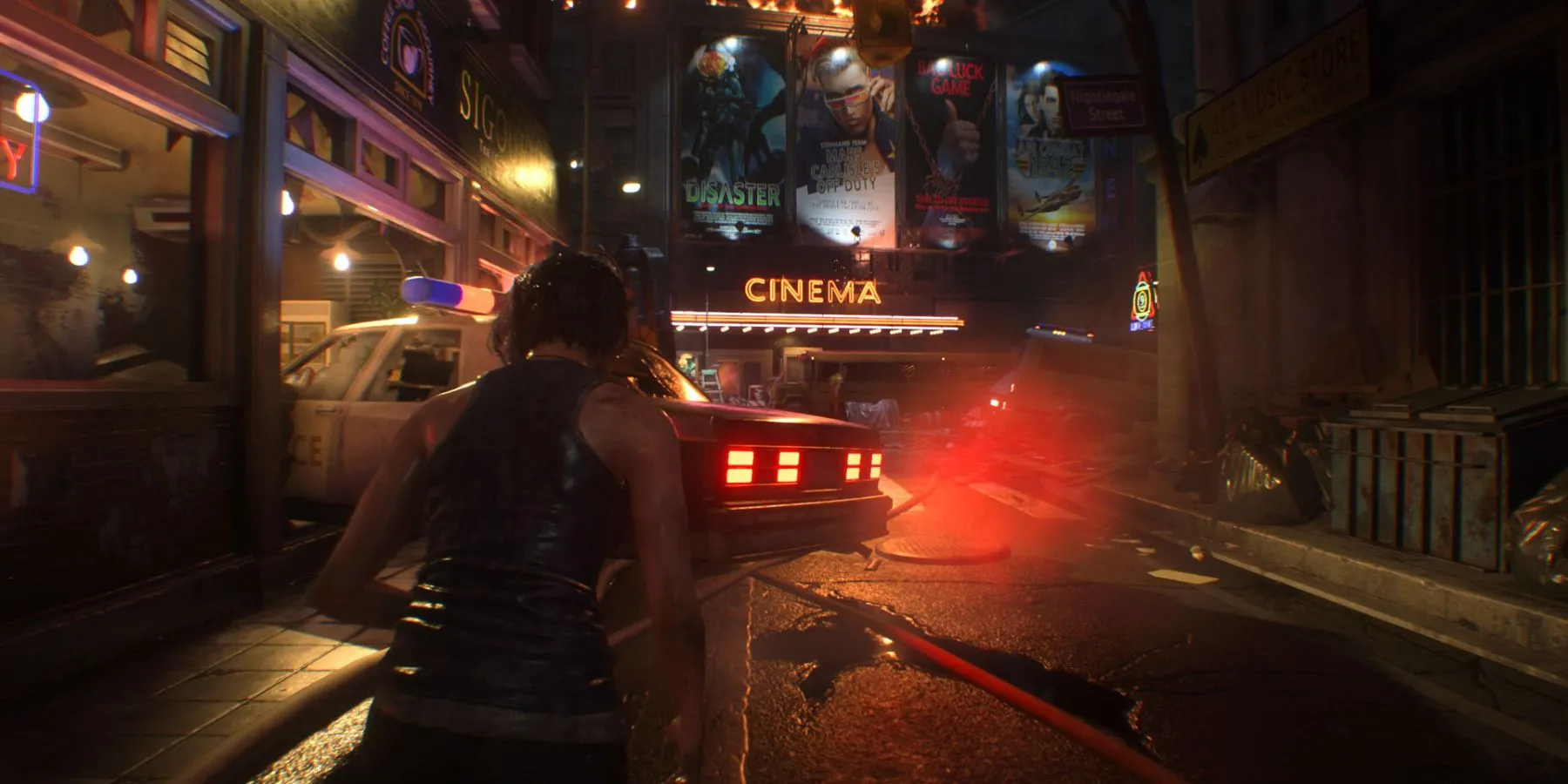 Jill Valentine trên đường phố Raccoon City với biển hiệu rạp chiếu phim và xe cảnh sát trong Resident Evil 3 Remake