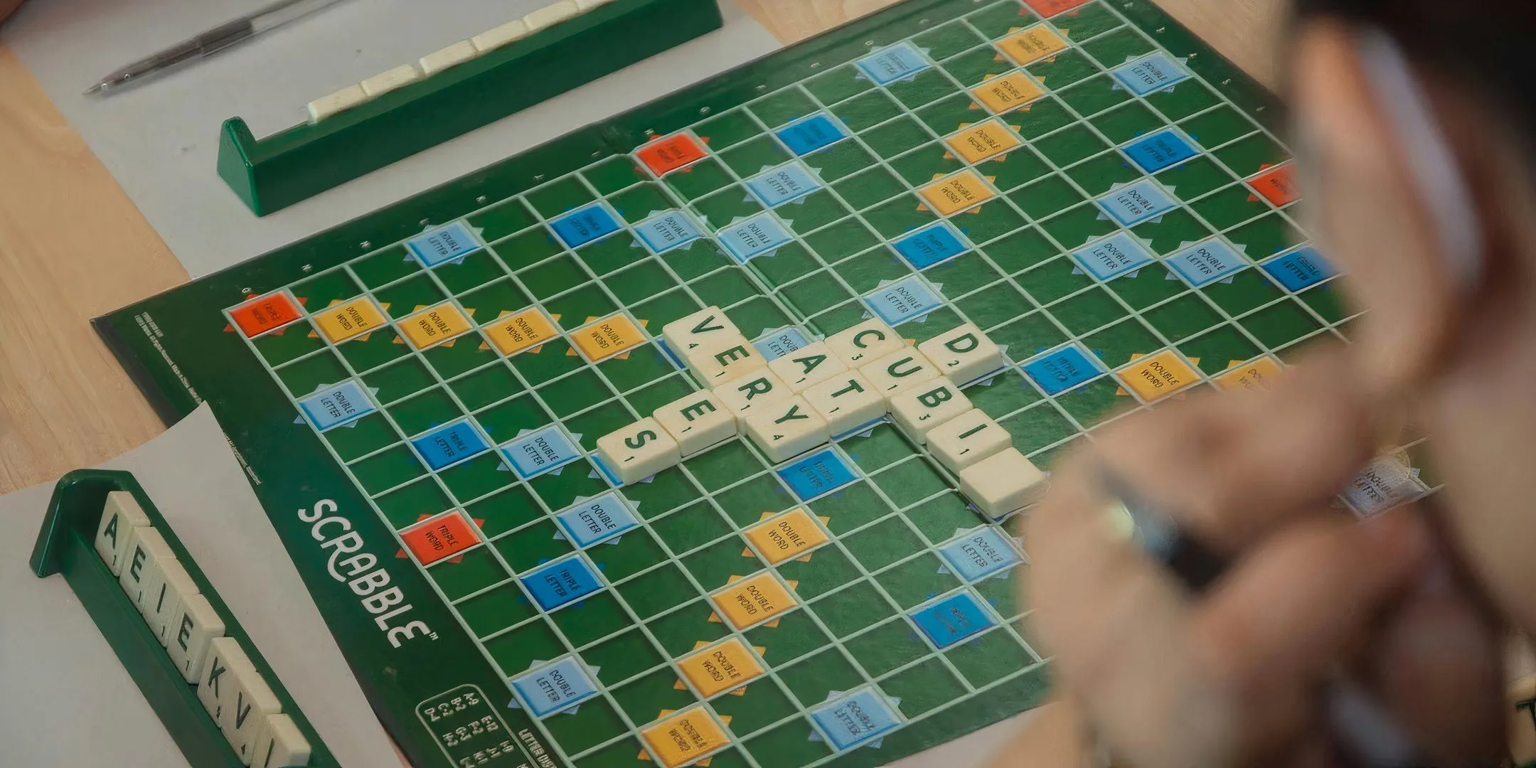 Bàn chơi Scrabble với các ô điểm và các chữ cái đang được sắp xếp, liên quan đến luật chơi từ ngữ và việc có cần biết nghĩa từ không.