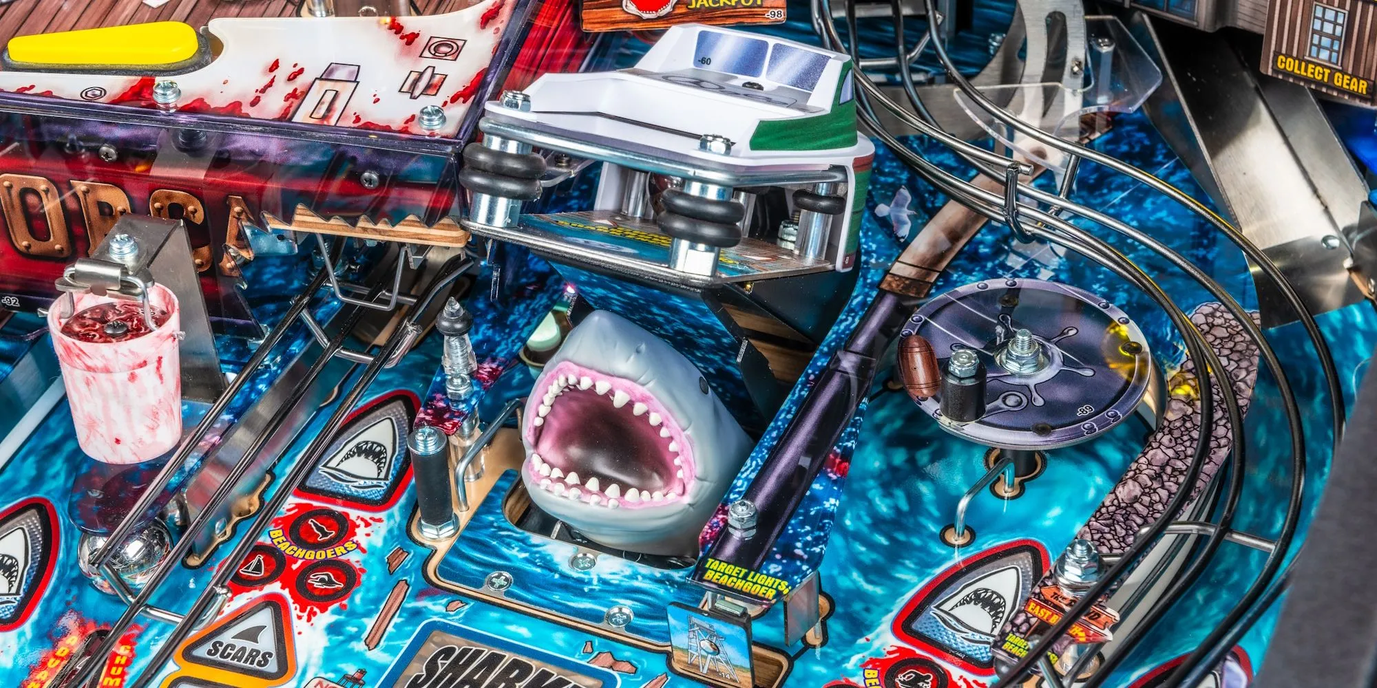 Hình ảnh máy pinball Jaws phiên bản Kỷ niệm 50 năm với viền đỏ kim loại, mặt chơi lấp lánh và đường ray màu đồng